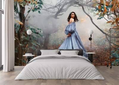 Queen woman walks in mystical autumn misty forest. Orange foliage gothic trees mist smoke. Hair flying in wind motion princess girl looks around. Medieval royal vintage long blue dress, puffy sleeves Wall mural