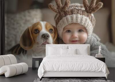 A cute baby boy dressed up as reindeer playing with an adorable Beagle dog in the living room at home during the winter season.  Wall mural