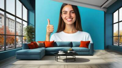 Smiling woman giving thumbs up on blue background
 Wall mural