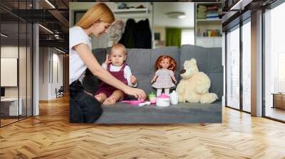 Happy mother and toddler daughter playing games with toys together in comfortable cozy house, having fun. Little girl and mummy spending leisure time, pretending eating from toys dish. Wall mural