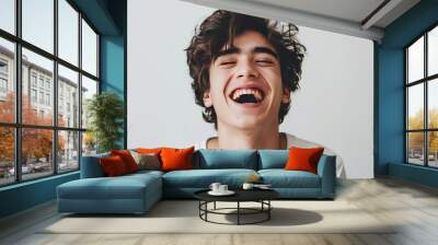 Close up view of a teenage boy with curly hair, isolated on a plain gray background. White shirt. Wall mural