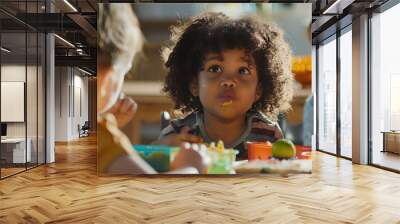 Preschool children eat lunch together at school, with colorful cutlery. Wall mural