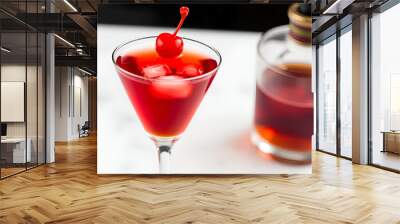 A red cocktail in a martini glass, garnished with a maraschino cherry on a toothpick.  whiskey-based cocktail, with a deep red color and amber hues, white background Wall mural