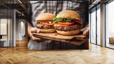 Close-up of a man holding a hamburger on a wooden cutting board. AI-generated images Wall mural