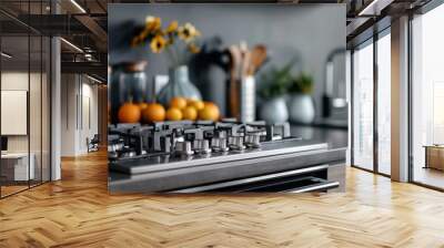 Close-up of a stainless steel gas stove in a modern kitchen with fruits, wooden utensils, and stylish decor. Wall mural