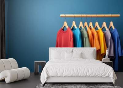 Colorful T-shirts on Hangers Against Blue Background Wall mural