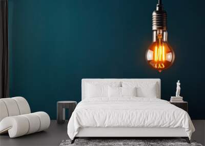 Industrial-style light bulb with a glowing filament suspended against a deep blue background. Suitable for creative or energy-related themes. Wall mural