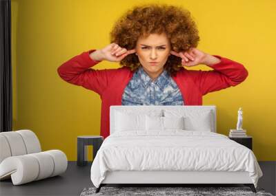 Don't want to listen you! Portrait of curly-haired woman looking angrily and closing ears to avoid unpleasant talk, annoyed by advice, ignoring communication. studio shot isolated on yellow background Wall mural