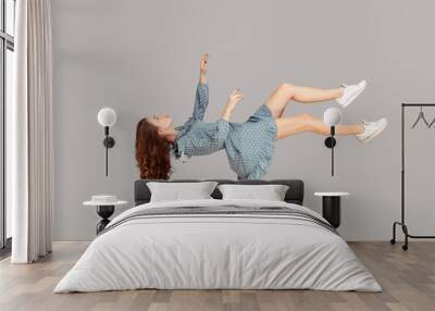 Floating in air. Relaxed girl in vintage ruffle dress levitating keeping eyes closed, sleeping while flying mid-air, having comfortable peaceful dream. full length studio shot isolated on gray, indoor Wall mural