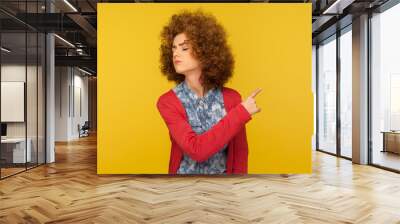 Get out! Portrait of upset vexed woman with curly hair showing exit, demanding to leave her alone, turning away with resentful irritated expression. indoor studio shot isolated on yellow background Wall mural