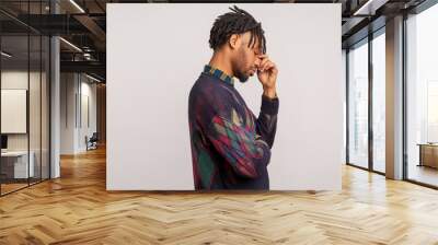 Profile portrait of deeply upset frustrated bearded african man with dreadlocks touching his face with hand, facepalm, depression. Indoor studio shot isolated on gray background Wall mural