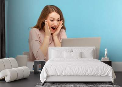 Wow! Surprised happy excited woman looking with amazement into laptop screen, reading shocking news or talking on video call, online communication. indoor studio shot isolated on blue background Wall mural