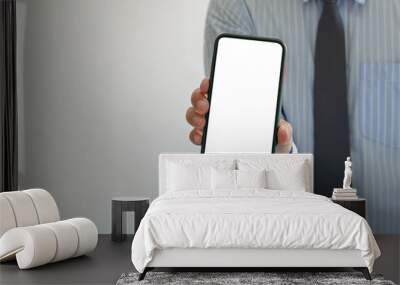 man holds a smartphone in hand. Mobile phone mockup white screen blank Standing Against. use for marketing advertising or promoting online product. Wall mural