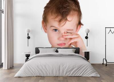 A tired little boy rubbing eyes, isolated on white Wall mural