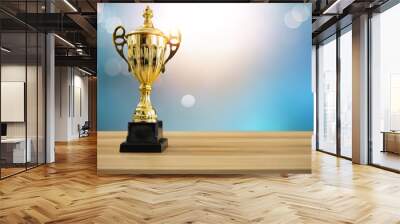 1st champion award, the best prize and winner concept, championship cup or winner trophy on wood table with soft blue and bokeh background Wall mural