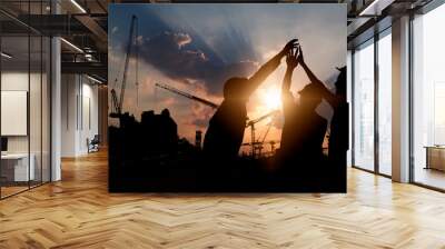 Engineer teamwork, silhouette of construction worker team touching hand together for power at working site Wall mural