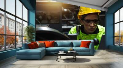 engineer woman wearing helmet and reflective vest in check and control industrial machine on tablet in industry, Wall mural