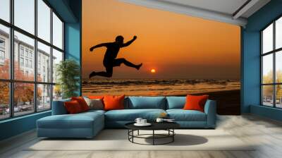 silhouette of a happy man jumping on a sunset Wall mural