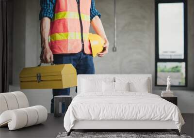 worker holding construction box and helmet preparing to work in working site Wall mural