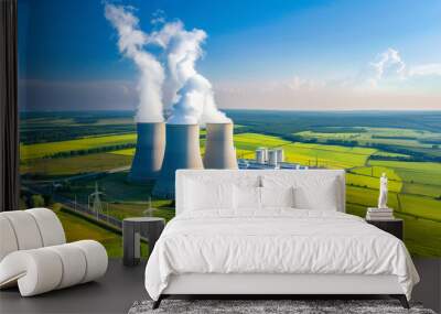 Aerial view of a modern nuclear power plant with cooling towers releasing steam, surrounded by green fields under a clear blue sky, representing clean energy and environmental sustainability. Wall mural