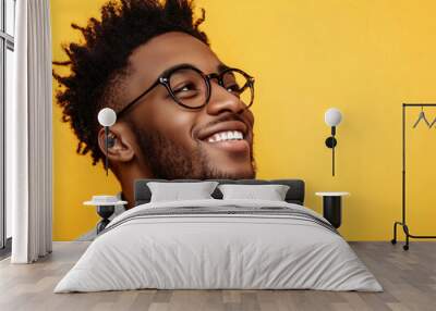 Smiling stylish Gen Z Black hipster guy looking away at copy space. Happy young African American man posing against a yellow background. Positive, confident, trendy male portrait for modern advertisin Wall mural