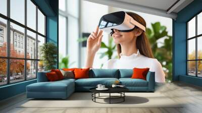 Smiling woman using a VR headset, enjoying an interactive and futuristic experience. Wall mural