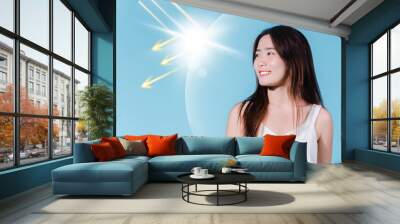 Smiling asian beauty woman hold sun cream with sun protection uv or sunscreen, sun block on the blue background Wall mural