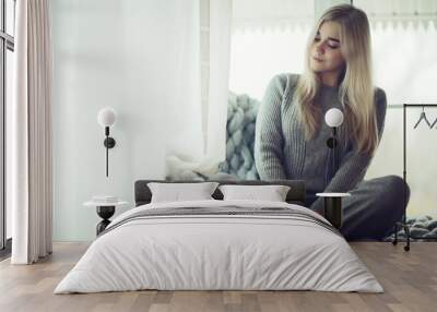 winter home interior, model girl basking in a knitted blanket at the window, a cold day at home Wall mural