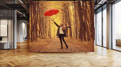 young woman dancing in an autumn park with an umbrella, spinning and holding an umbrella, autumn walk in a yellow October park Wall mural