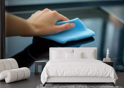 Woman polishing an induction cooktop with a blue microfiber cloth. Wall mural