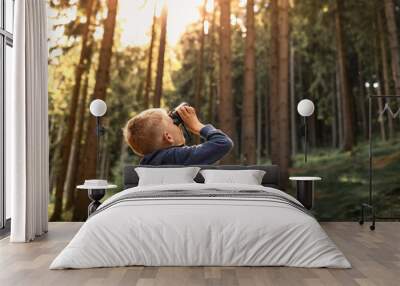 Child in the forest looking through binoculars exploring nature and wildlife  Wall mural