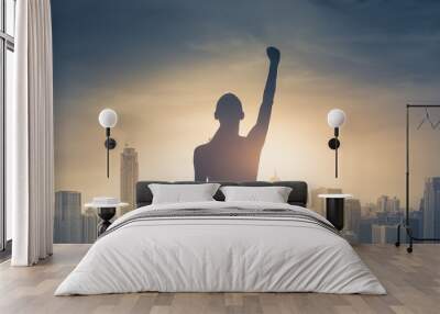 confident young woman with fist in the air facing the city. People power and strong young woman concept  Wall mural