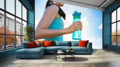 Drink water to stay health. Female runner holding a bottle of water.  Wall mural