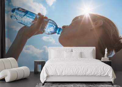 Female drinking bottle of water on a hot summer day. Wall mural