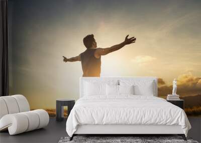 Finding happiness and freedom. Na with open arms feeling at peace in nature sunset  Wall mural