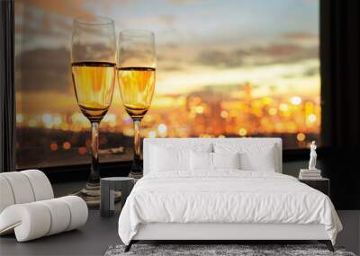 Glasses of champagne against city sunset. Wall mural