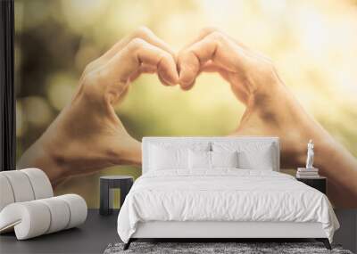 Hand making heart against green nature background.  Wall mural