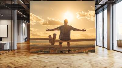 Happy man sitting outdoors looking up to the sky with arms outstretched. People freedom and happiness concept.  Wall mural