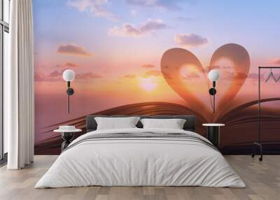 Heart shape from book against peaceful sunset. Reading, religion, love concept. Double exposure.  Wall mural