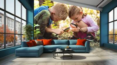 Kids exploring in forest with a magnifying glass. Wall mural