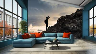 Man getting ready to climb up mountain looking up at the challenge before him. Believe in yourself, overcoming challenges, pushing forward concept.  Wall mural