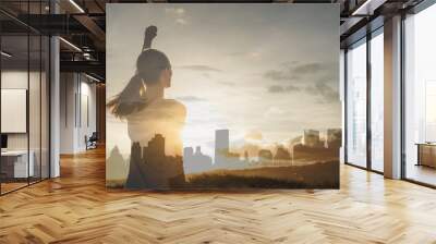 Modern day woman supper hero in the city. Strong young woman with fist In the sky facing the city sunset  Wall mural