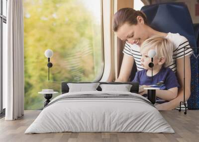 Mother and one year old son riding a train through the country side. Wall mural