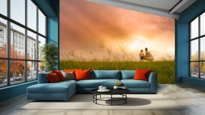 Mother and son spending time together outdoors watching the beautiful sunset in a grass field.  Wall mural