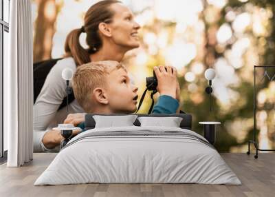 Mother child together hiking in the forest looking through binoculars bird watching exploring learning about nature, family adventure  Wall mural