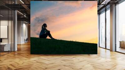 People enjoying nature. Woman sitting on a hill watching the sunrise.  Wall mural