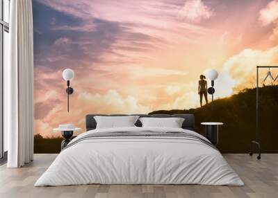 silhouette of woman standing on top of mountain watching the sunset Wall mural