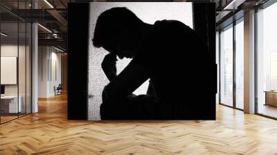 silhouette of young man feeling sad, tired sitting in a dark room Wall mural