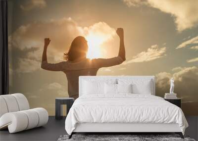 Strong and determined young woman flexing her arms up to the sunset sky. People power, and strength concept  Wall mural