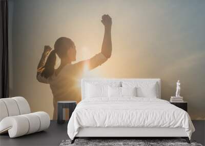 Strong confident woman flexing arms facing the sunset.  Wall mural